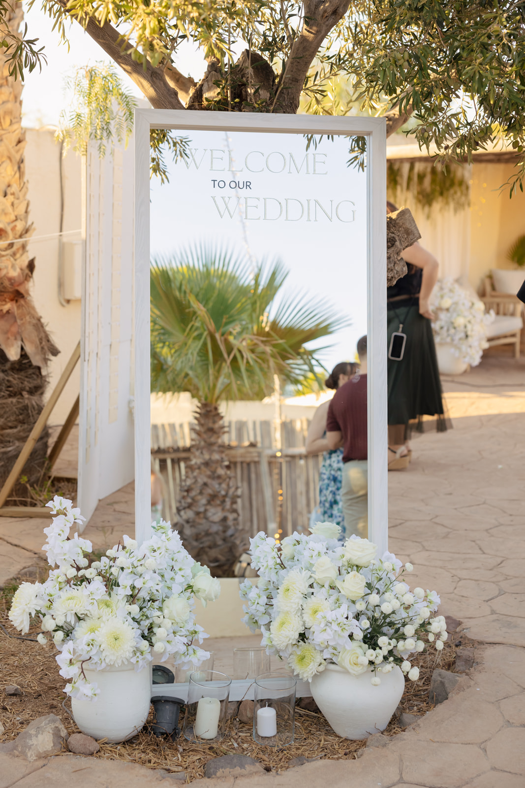 Welcome to our Wedding Spiegel mit weissen Blumenstiraeusson und Kerzen davor, Olivenbaum, Cortijo El Sotillo San Jose