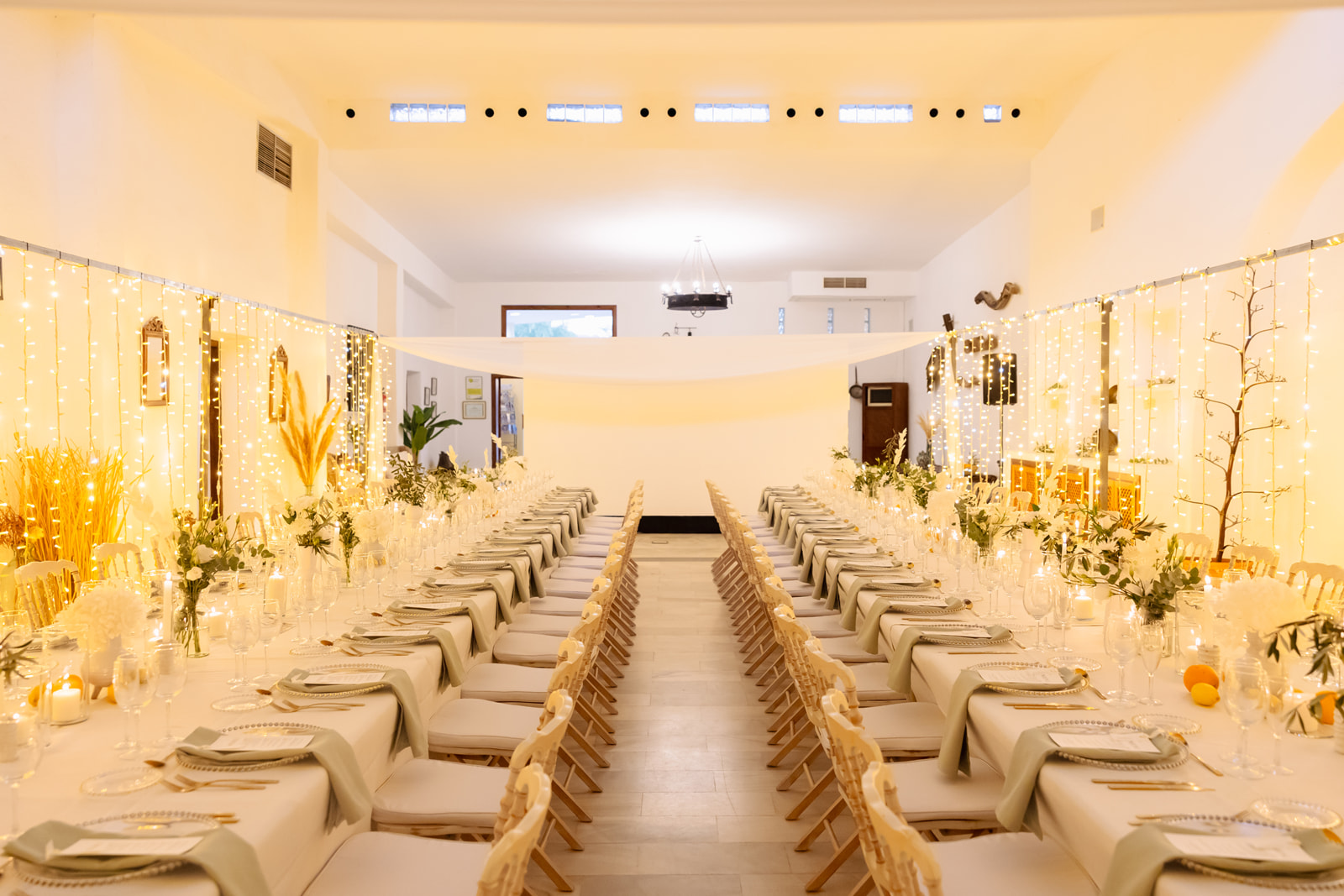 Gesamtansicht des leeren Dinnerraums im Cortijo El Sotillo - zwei lange Tische, fallende Lichterketten, weisses Blumendekor, Hochzeit Spanien
