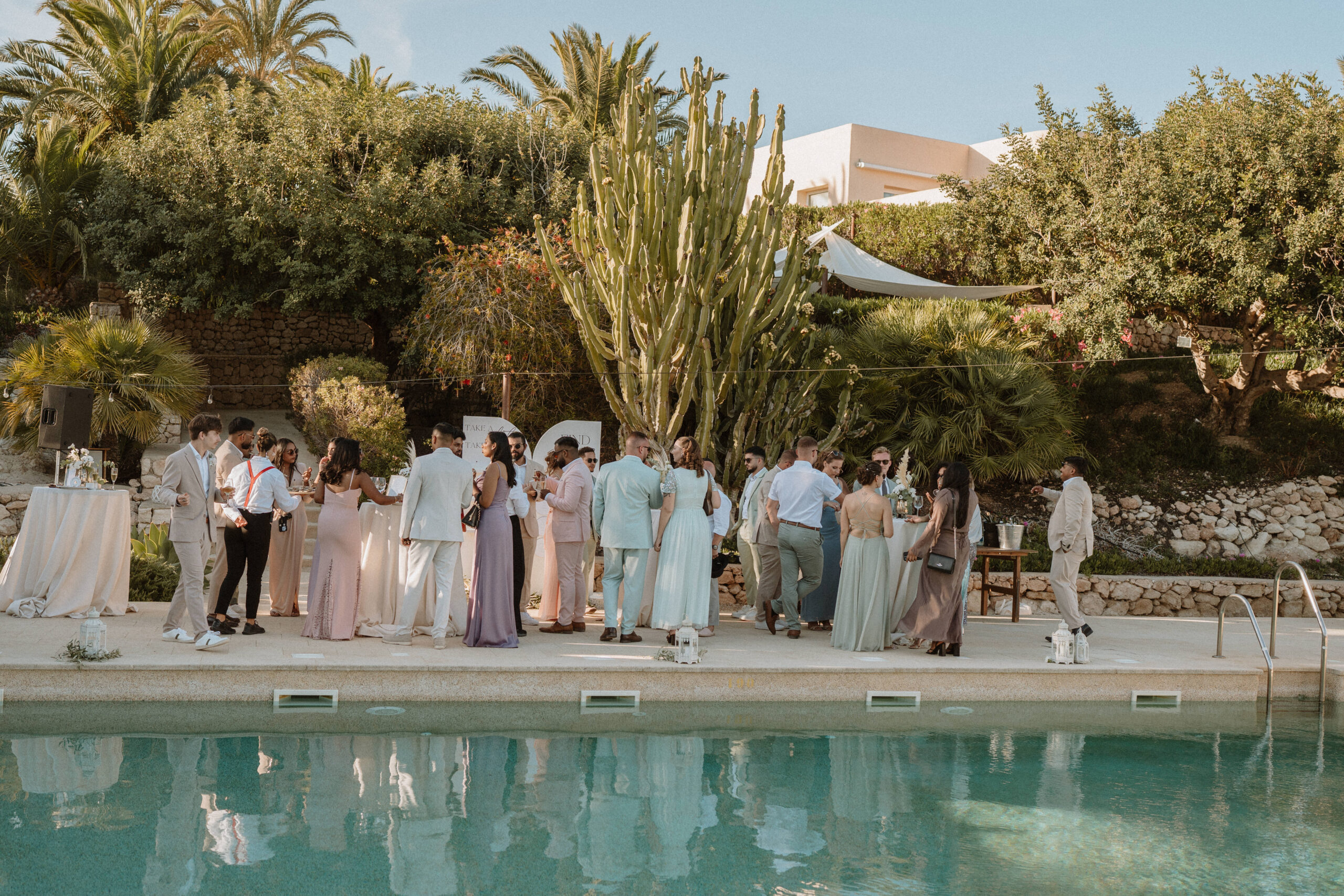 Gäste bei der Cocktailstunde am Pool mit Kaktus, Destination Wedding Spanien