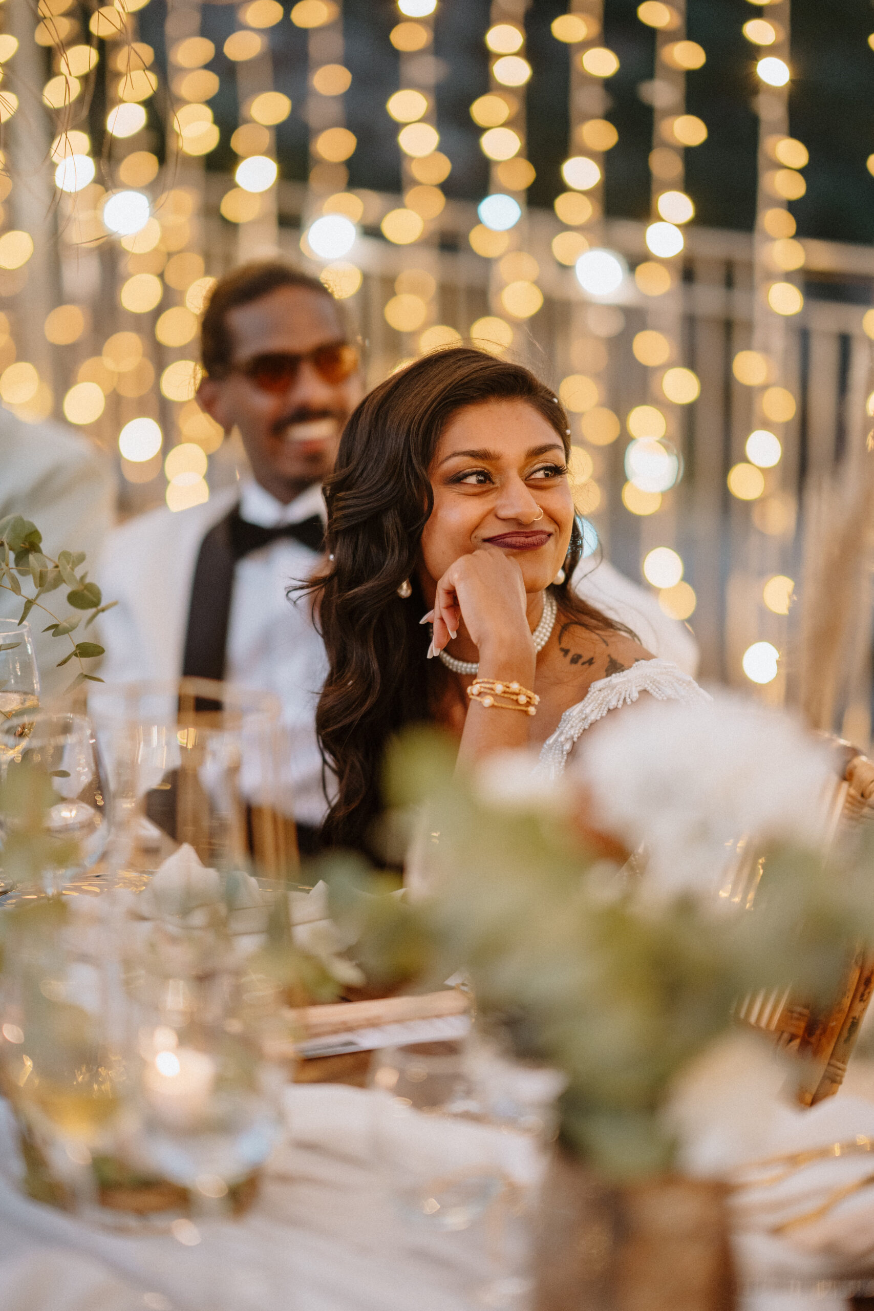 Braut beim Abendessen lachend unter Lichterketten, Destination Wedding