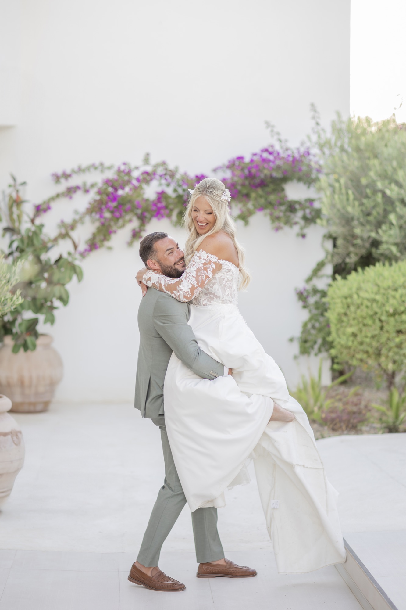Braeutigam hebt die Braut vor Bougainvillea, El Paraiso al Mar Guardias Viejas, Boho-Strandhochzeit
