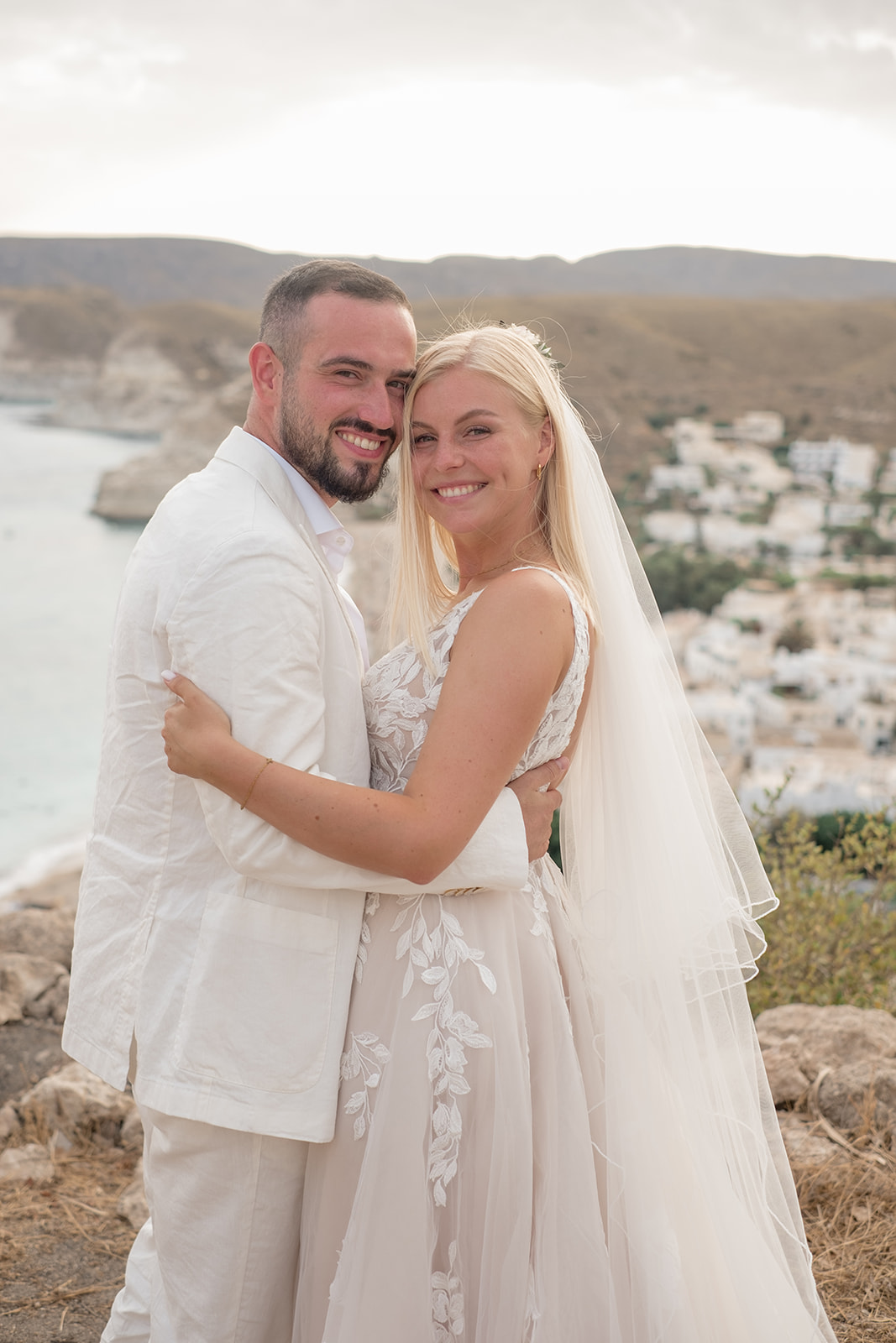 Brautpaar Lara und Michael lächeln gemeinsam in die Kamera auf dem Felsen mit Blick auf Agua Amarga und das Mittelmeer