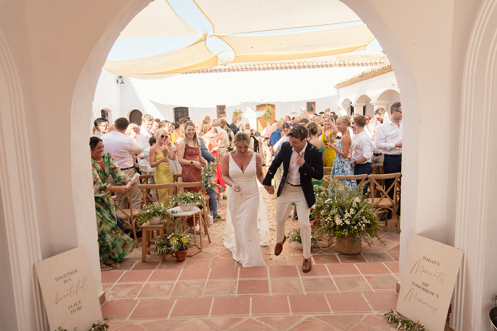 Bride and groom walking back down the aisle through the archway, guests applauding in the courtyard, finca near Mojacar, finca wedding Andalusia