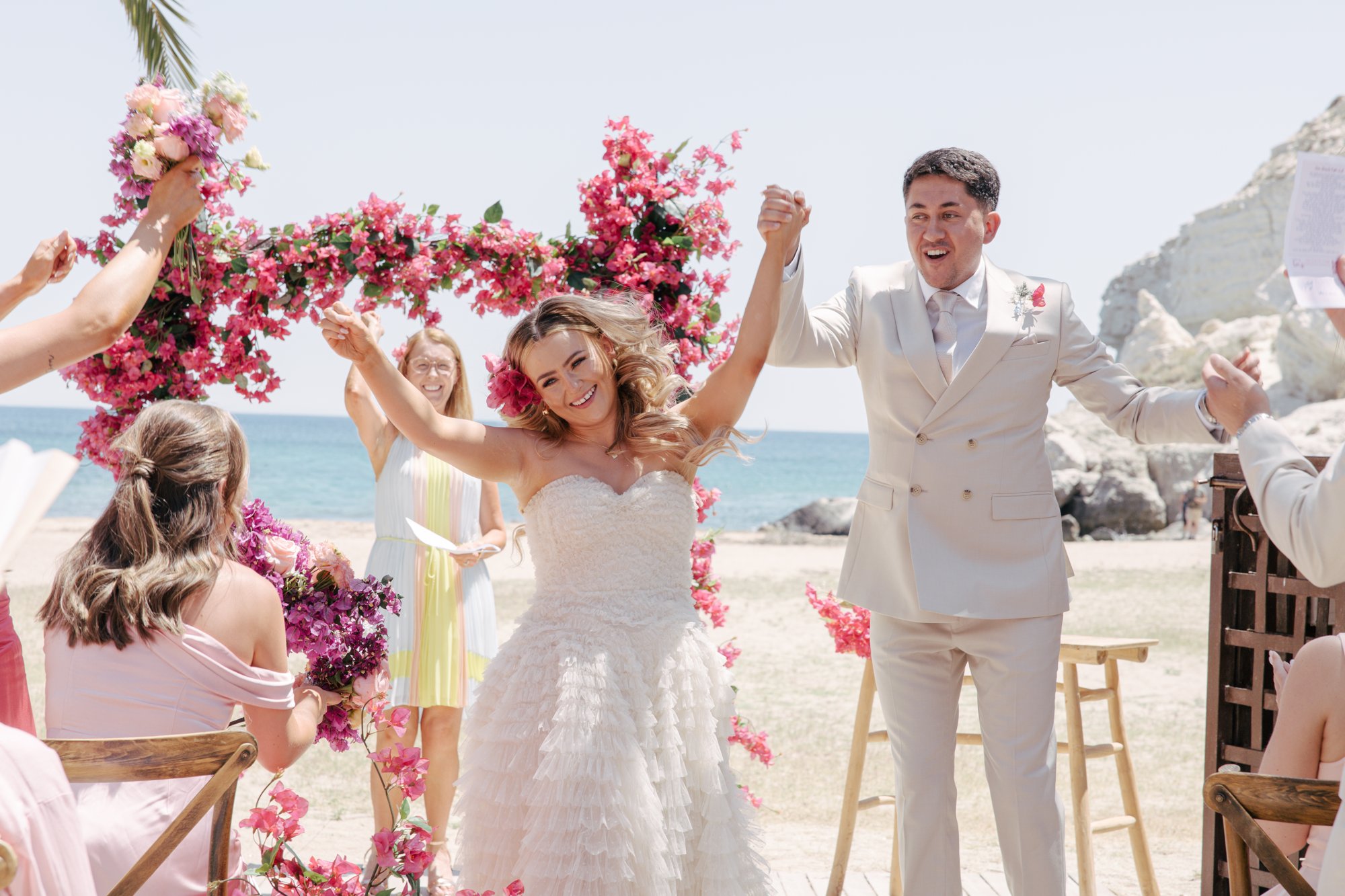 Bride and groom cheering under the bougainvillea arch, El Beach Agua Amarga, beach wedding Cabo de Gata