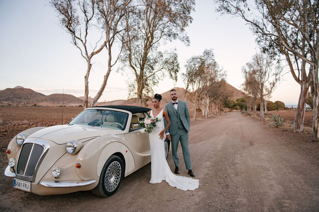 Brautpaar am cremefarbenen Oldtimer-Cabrio auf einer Eukalyptus-Allee, Cabo de Gata, elegante Destination Hochzeit