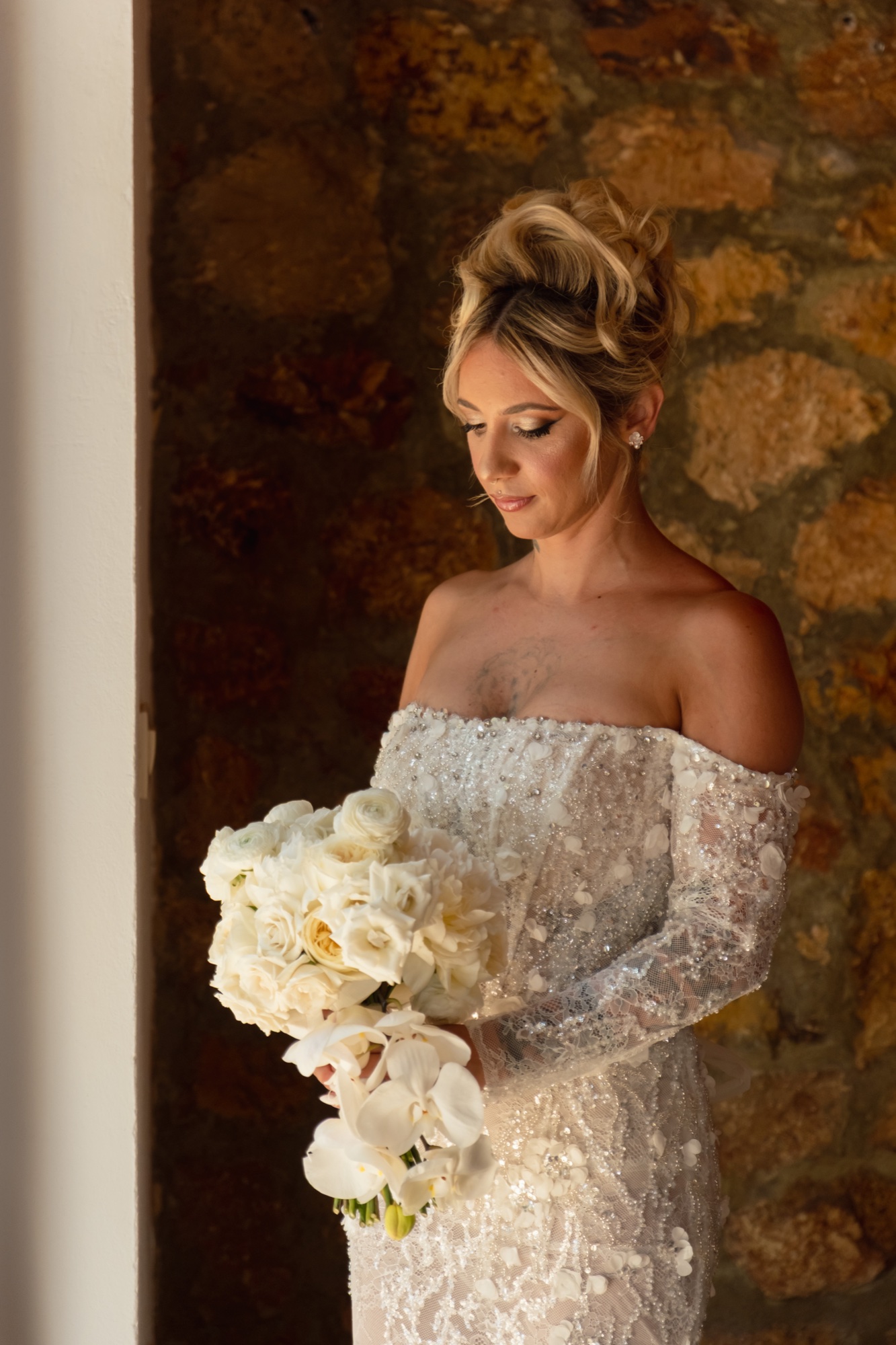Braut Christina mit weißem Brautstrauß vor Natursteinwand, Location 17 Almería, Spitzenkleid