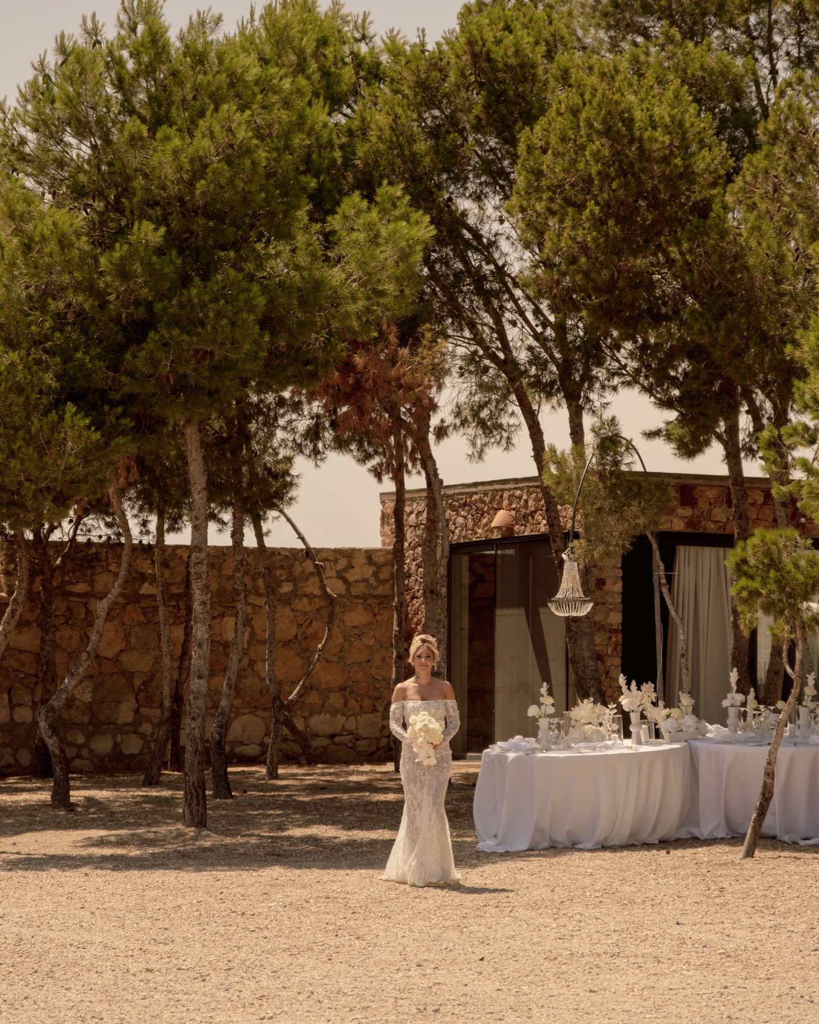 Braut Christina allein vor der gedeckten Tafel im Pinienhain, Location 17 Cabo de Gata, Hochzeit ganz in Weiß