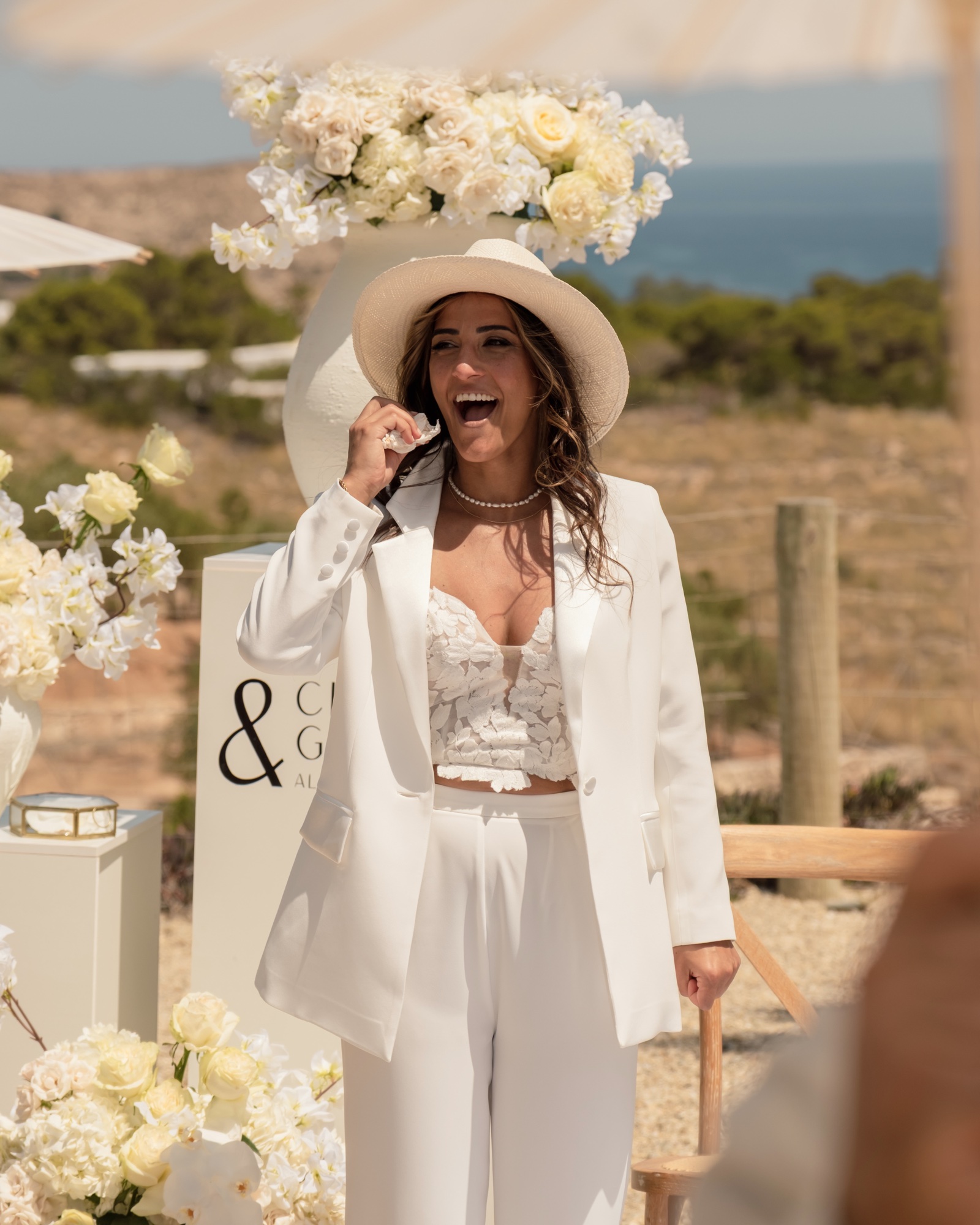 Braut Giusi lacht und weint am Altar, weißer Anzug mit Panamahut, Location 17 Cabo de Gata, gleichgeschlechtliche Hochzeit in Spanien