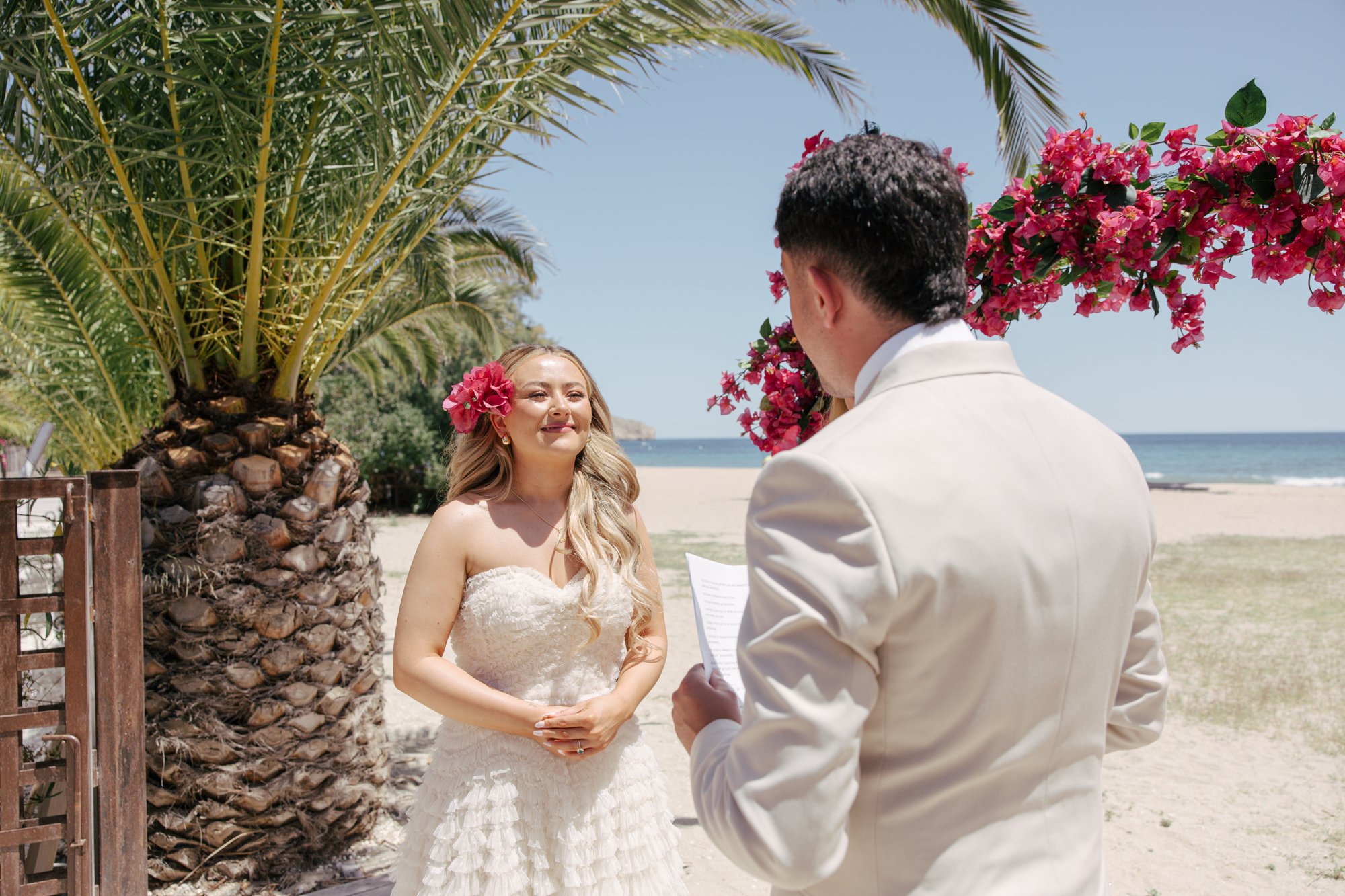 Couple exchanging vows at the flower arch, El Beach Agua Amarga, beach wedding Cabo de Gata