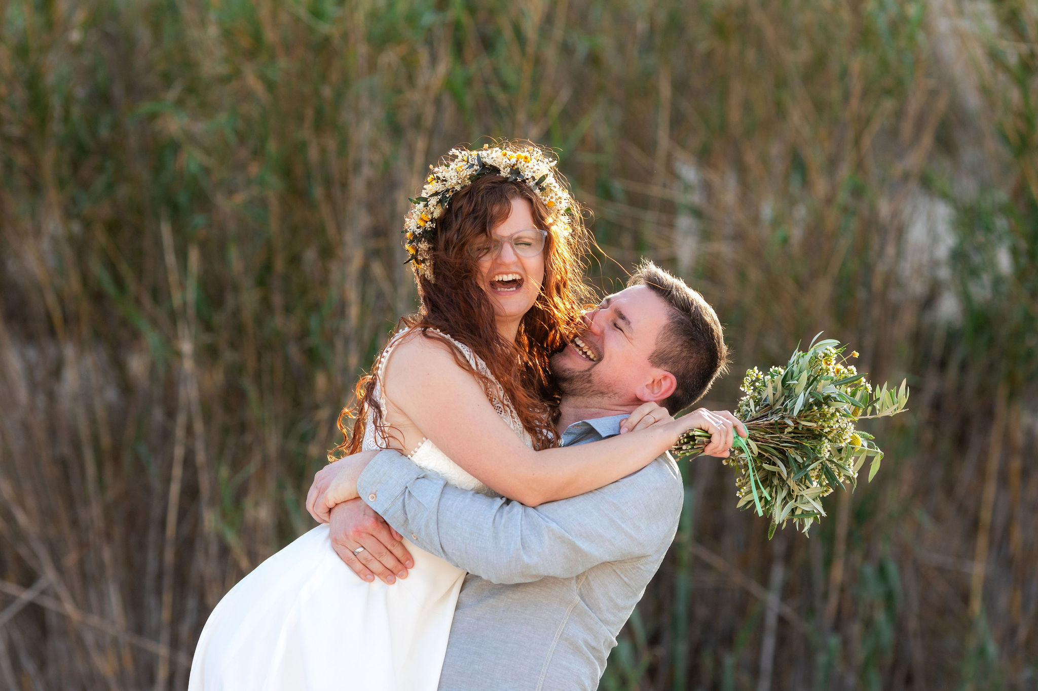 Brautpaar lacht in der goldenen Stunde, Bräutigam hebt die Braut hoch, Cabo de Gata, Boho Strandhochzeit