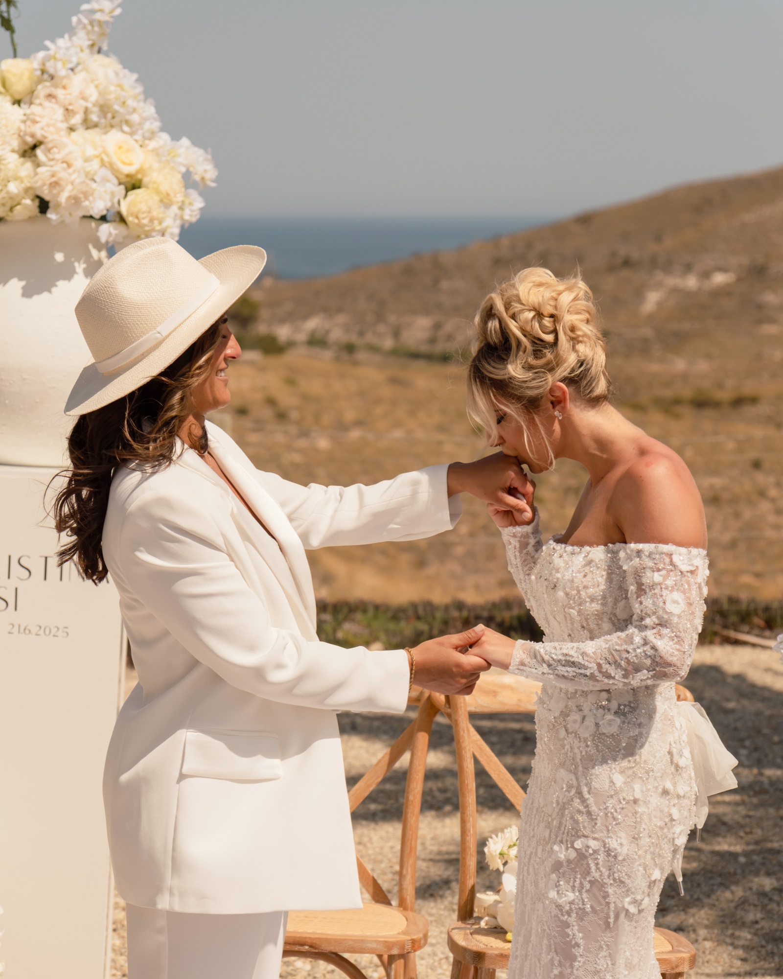 Eine Braut küsst der anderen die Hand während der Trauung, Location 17 Cabo de Gata, zwei Bräute
