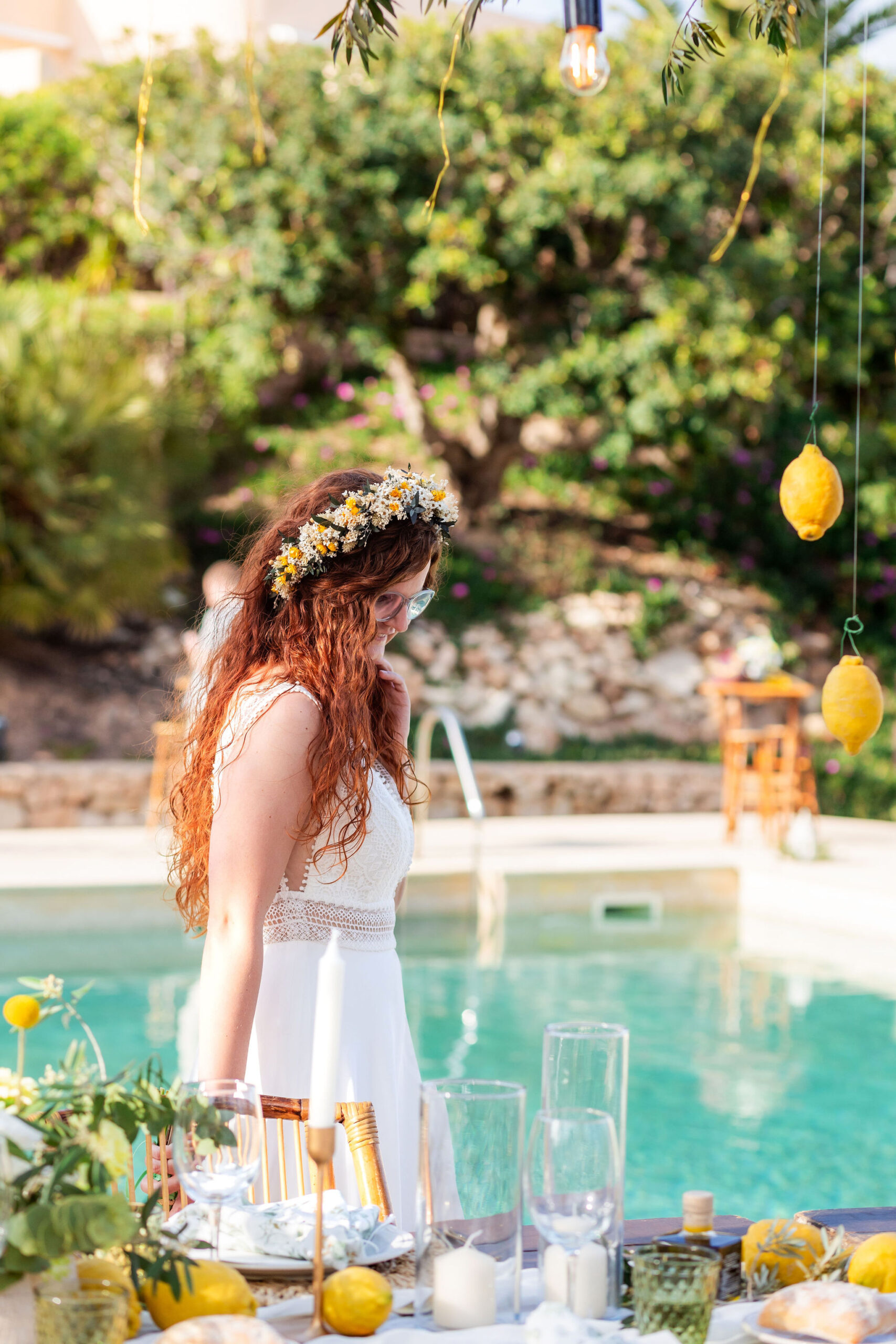 Braut mit Blumenkranz an der zitronengeschmückten Hochzeitstafel, Cabo de Gata, Boho Strandhochzeit
