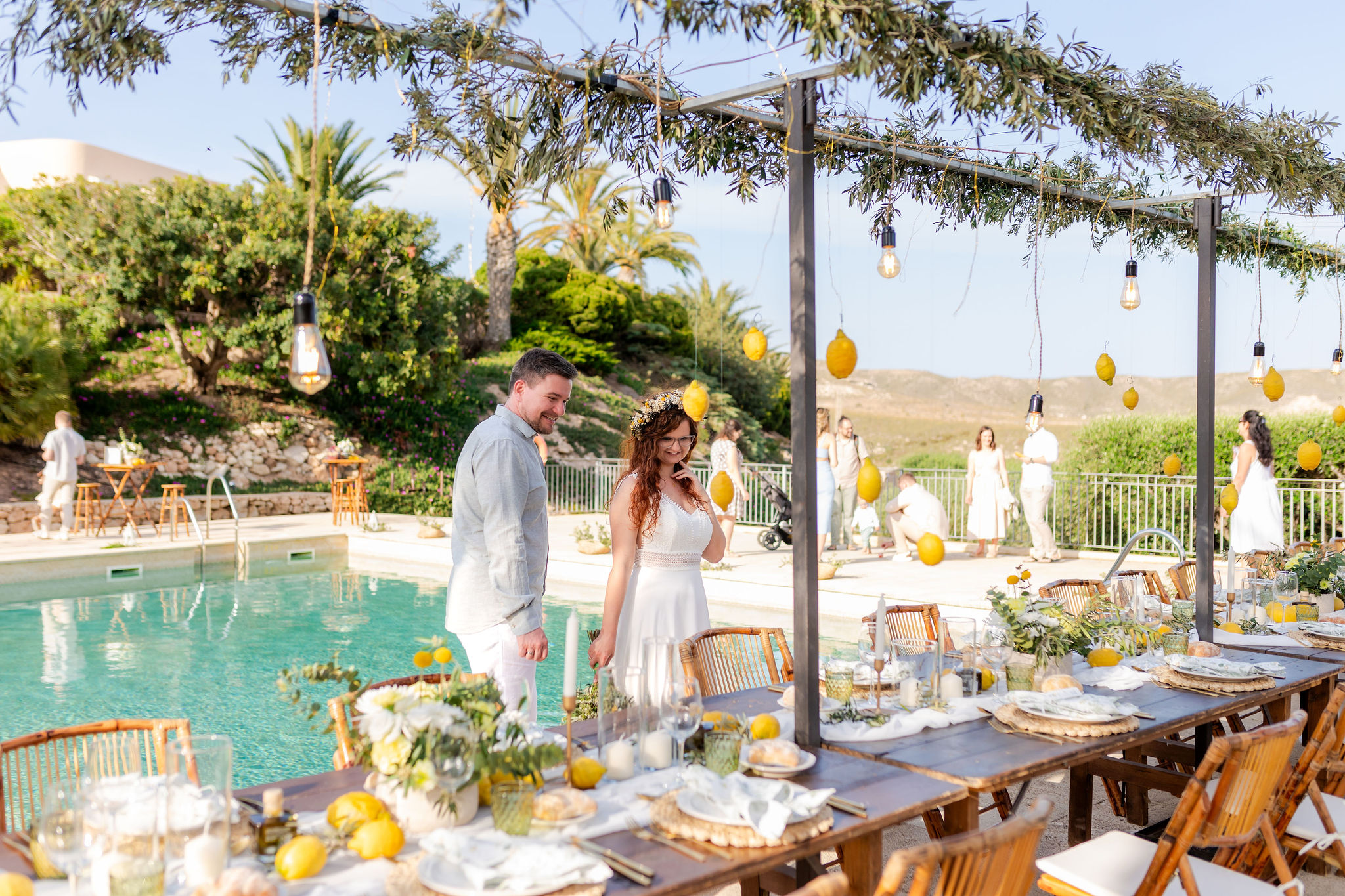 Brautpaar an der Pooltafel mit Zitronendeko und Olivenzweigen, Cabo de Gata, Boho Strandhochzeit