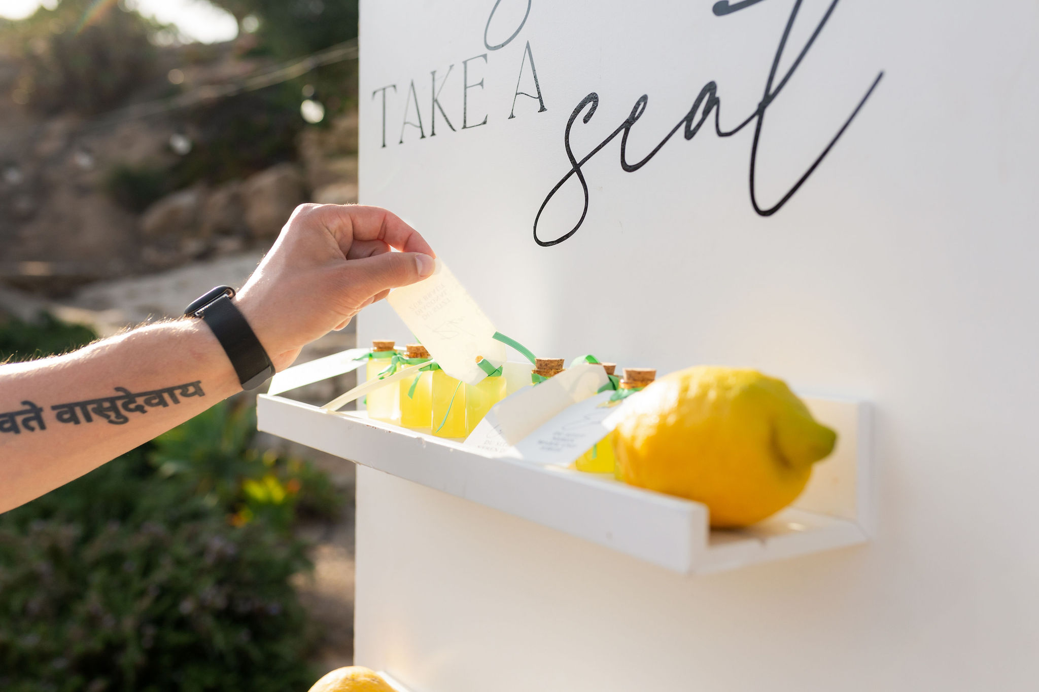 Gast nimmt ein Limoncello-Fläschchen vom Sitzplan, Boho Strandhochzeit Cabo de Gata