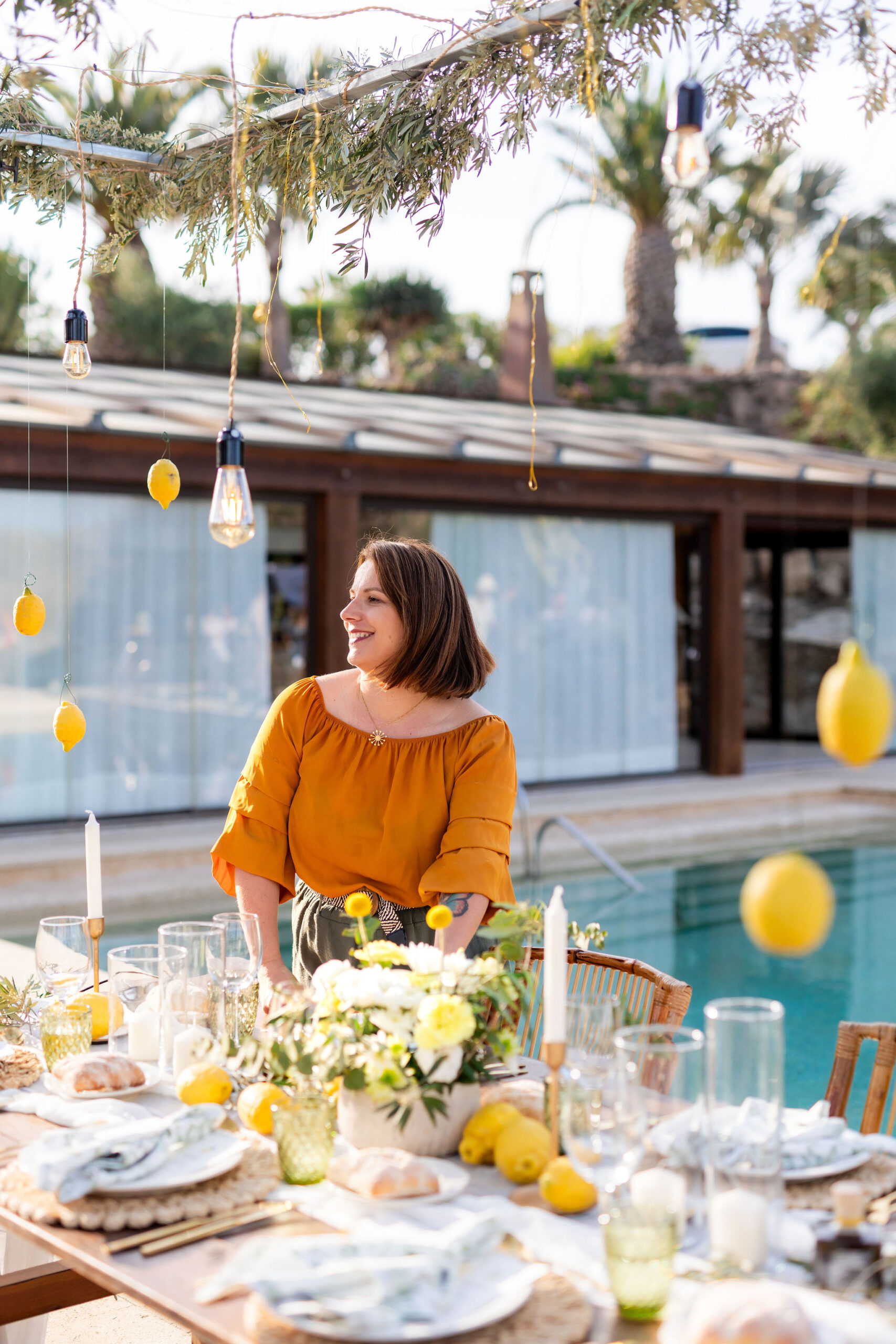 Hochzeitsplanerin Anna an der festlich gedeckten Tafel mit hängenden Zitronen, Boho Strandhochzeit Cabo de Gata