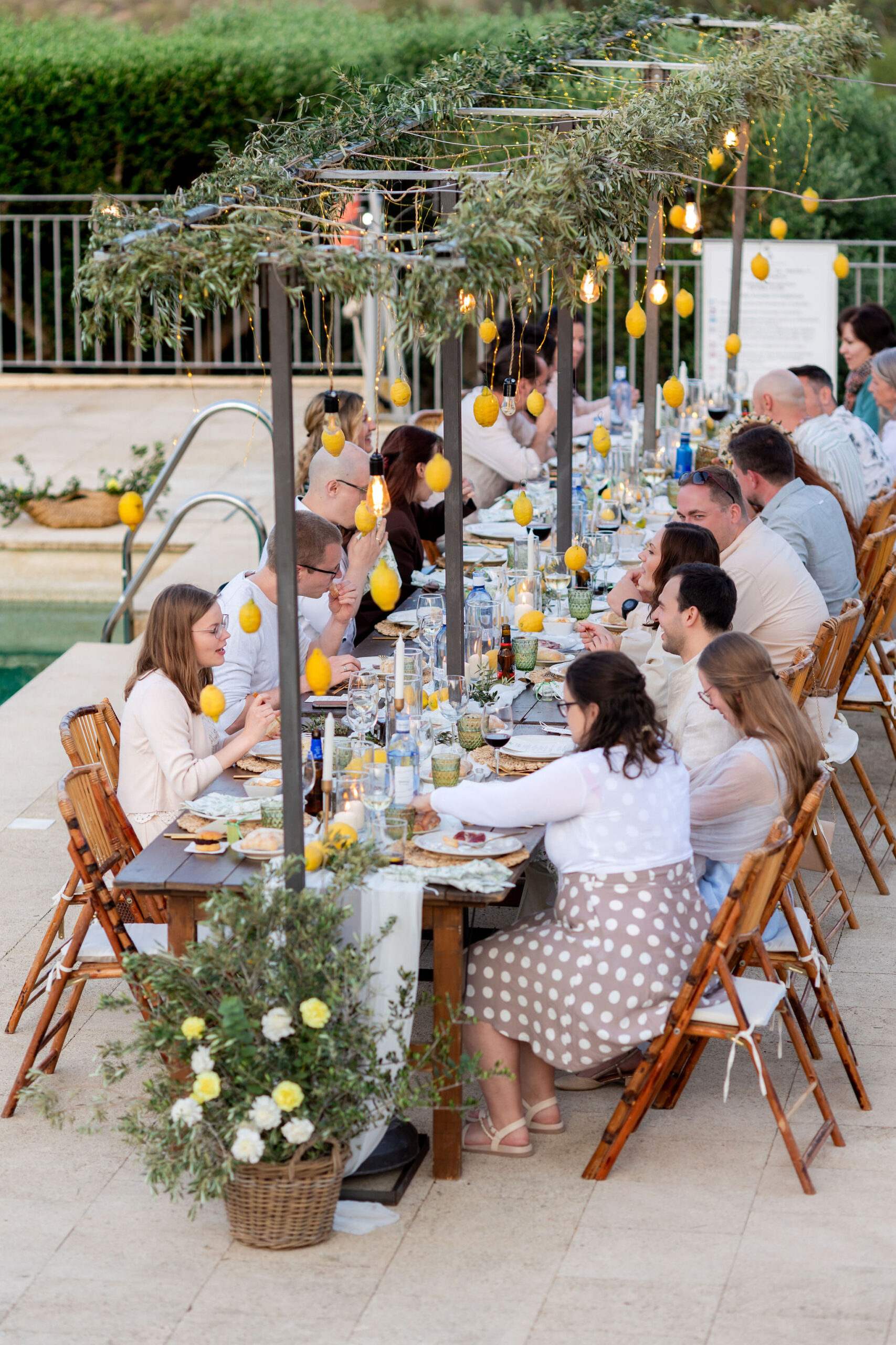 Gäste beim Dinner an der langen Pooltafel mit hängenden Zitronen, Boho Strandhochzeit Cabo de Gata