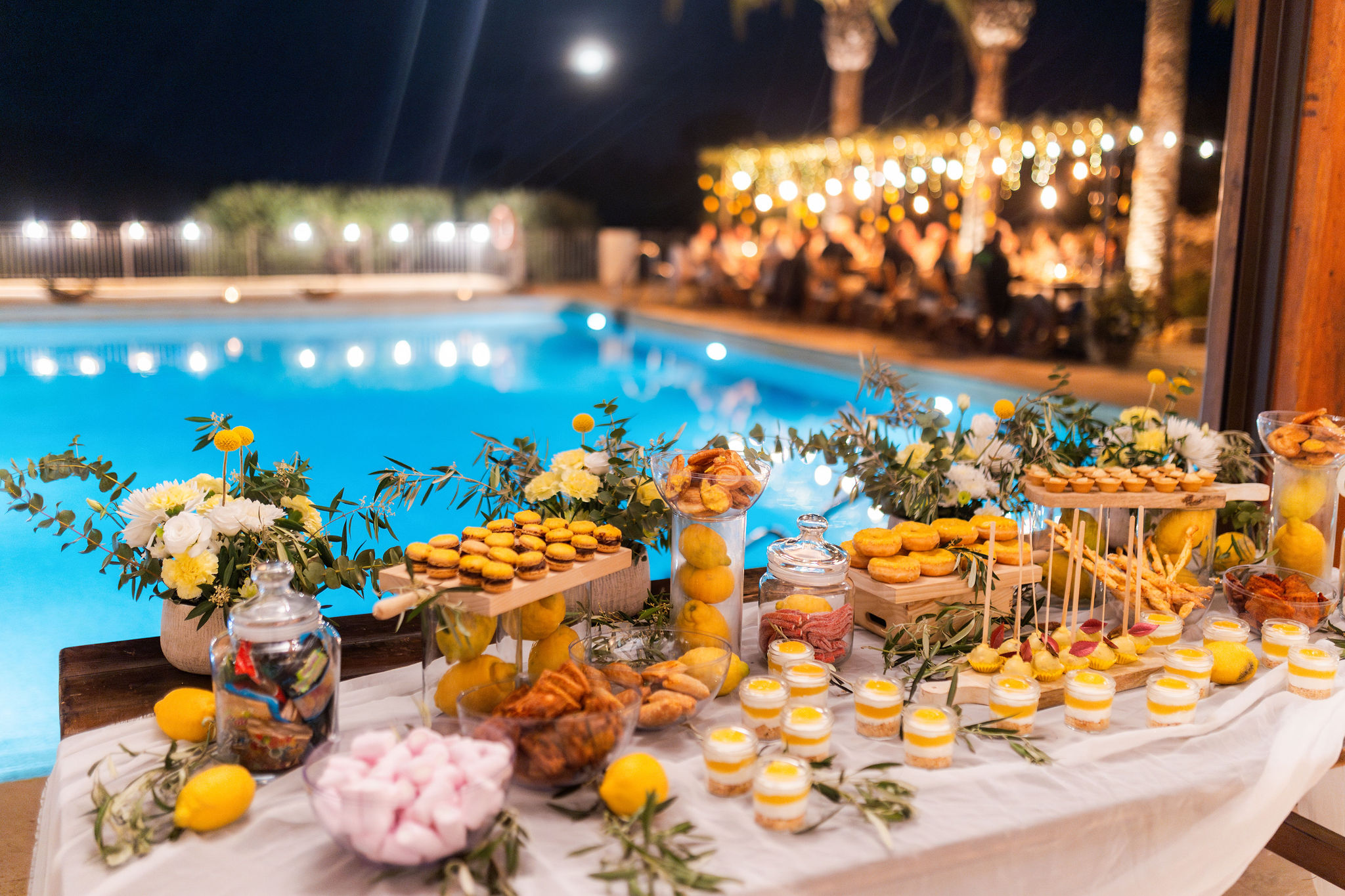 Dessertbuffet bei Nacht am beleuchteten Pool, im Hintergrund die leuchtende Tafel, Boho Strandhochzeit Cabo de Gata