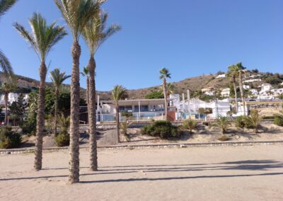 Breiter Sandstrand mit Palmen vor der weißen Beachbar in Mojácar