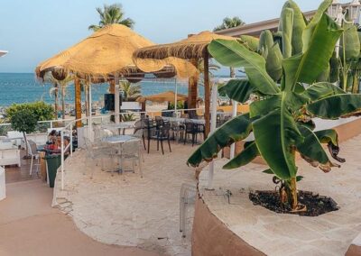 Strohschirme und Bananenstauden am Sand vor der Beachbar in Mojácar