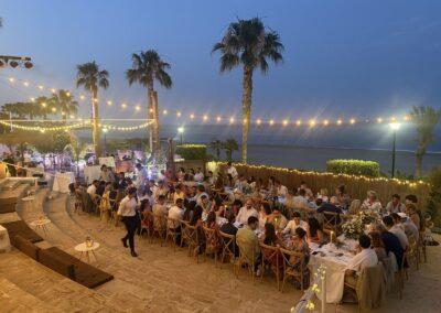 Hochzeitstafeln bei Sonnenuntergang unter Lichterketten am Strand von Mojácar