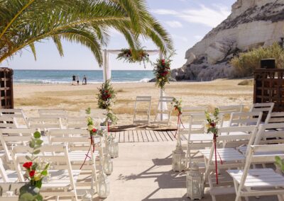 Traubogen mit Blumen direkt im Sand am Strand von Agua Amarga, dahinter Kliff und Meer