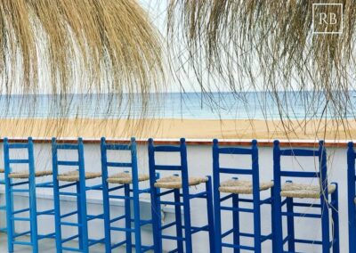 Blau gestrichene Barhocker mit Binsengeflecht vor dem Strand von Agua Amarga
