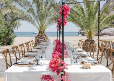 Hochzeitstafel mit pinker Bougainvillea vor Palmen und Meer