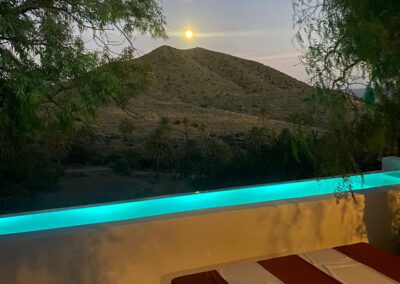 Beleuchteter Pool in der Dämmerung vor dem Bergkegel von Cabo de Gata