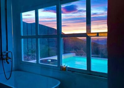 Freistehende Badewanne mit Fenster auf Pool und Sonnenuntergang