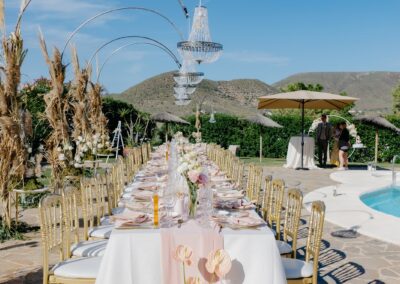 Hochzeitstafel mit hängenden Kronleuchtern und Pampasgras am Pool