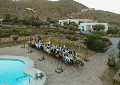 Hochzeitstafel am Pool von oben, umgeben von Garten und Hügellandschaft