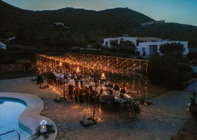Beleuchtete Hochzeitstafel am Pool bei Nacht, Lichterketten über der Gesellschaft