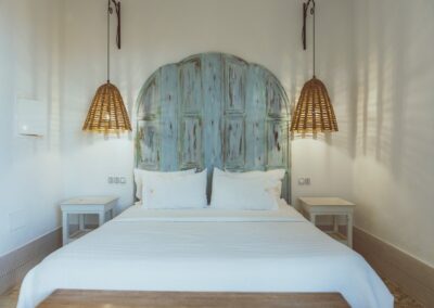 Gästezimmer mit blauem Kopfteil und Rattanlampen in der Anlage bei Pozo de los Frailes