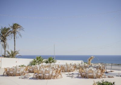 Runde Hochzeitstische zwischen Palmen mit Blick aufs Meer, weiße Feier-Location bei Guardias Viejas