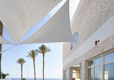 Weiße Sonnensegel über der Terrasse mit Palmen und Meer