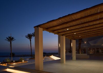 Beleuchtete Pergola am Abend über der Terrasse mit Palmen
