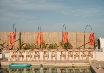 Festlich gedeckte Tafel entlang des Pools mit hängender Blumendekoration