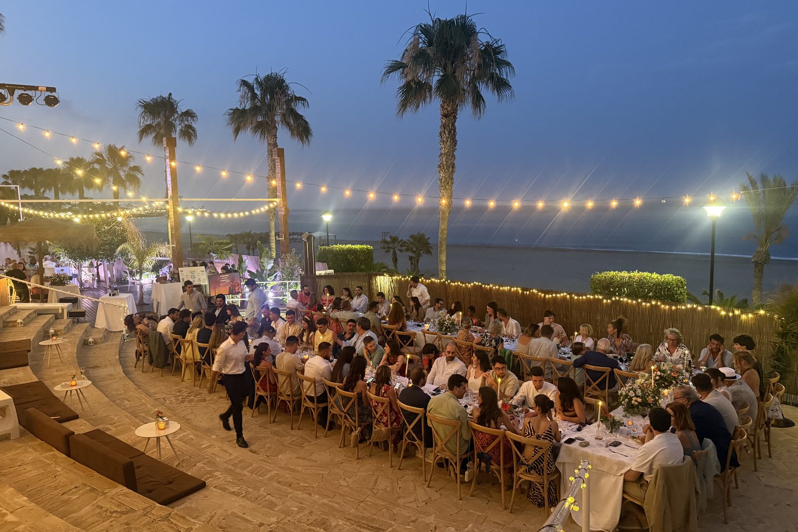 Gedeckte Hochzeitstische unter Palmen direkt am Strand einer weißen Beachbar in Mojácar