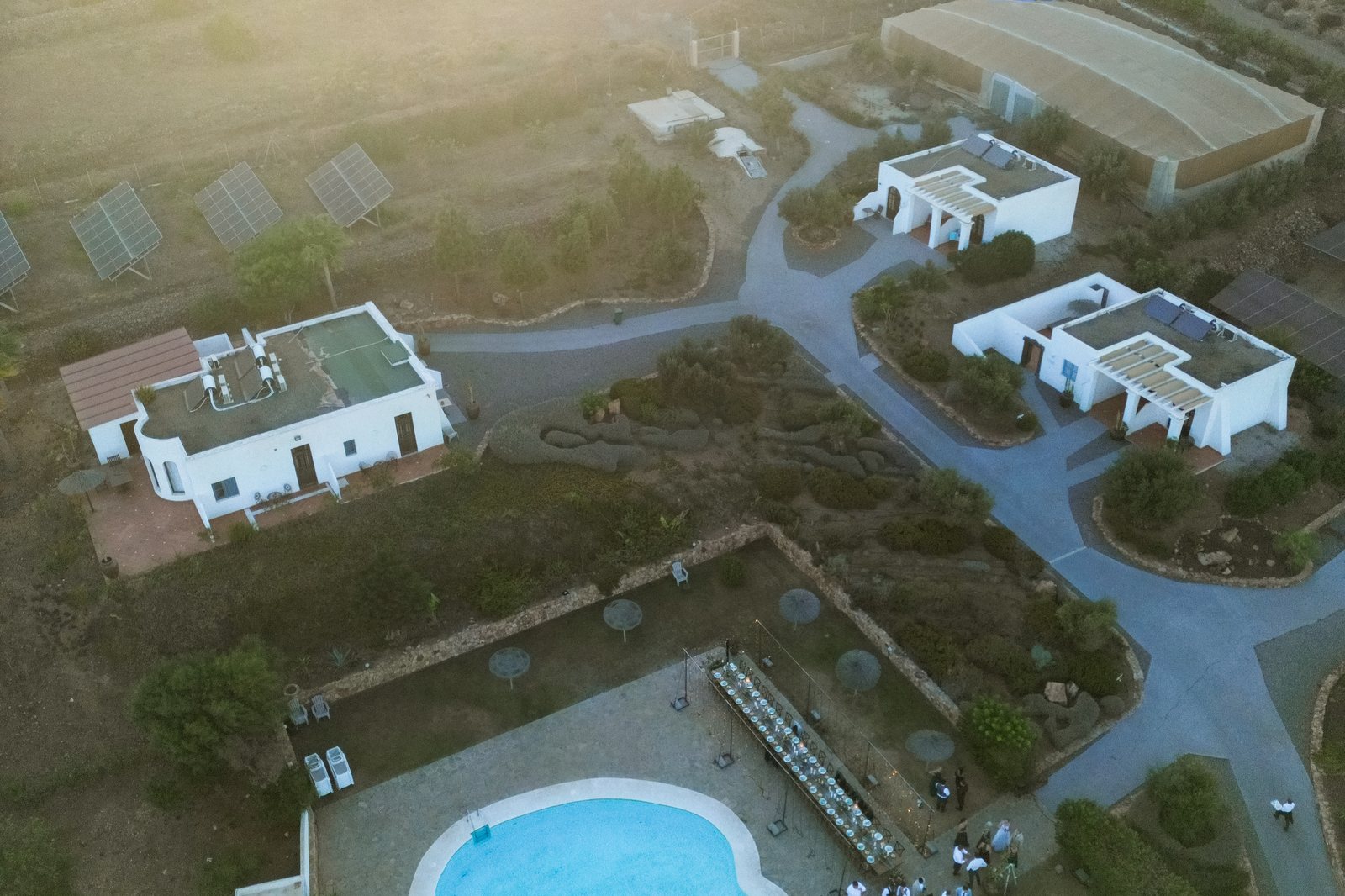 Luftaufnahme einer Hochzeit bei Nacht: beleuchteter Pool und Lichterketten über der Gartenanlage bei Pozo de los Frailes