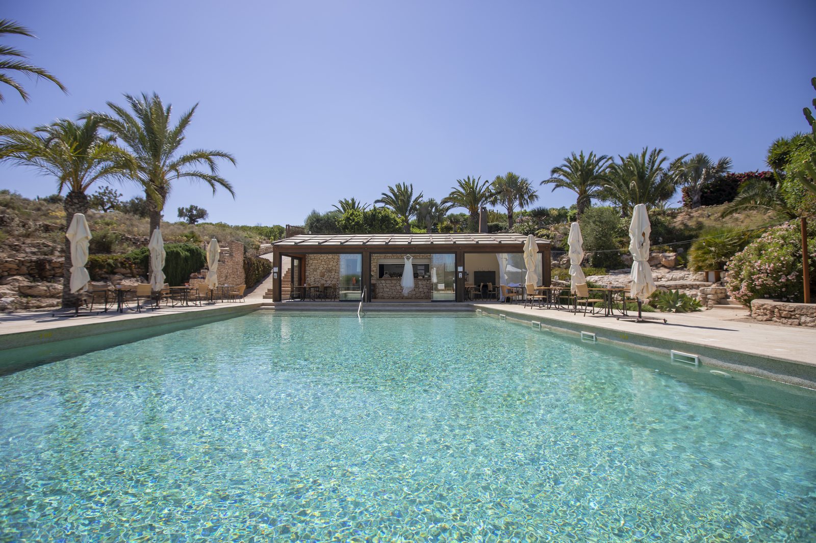 Großer Pool zwischen Palmen in einem ruhigen Hotel über Agua Amarga, Hochzeitslocation in Cabo de Gata