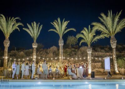 Angestrahlte Palmen über der Hochzeitsgesellschaft am Pool bei Nacht