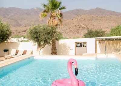 Türkisfarbener Pool des Cortijo an einem Sommertag, Palmen und Berge im Hintergrund