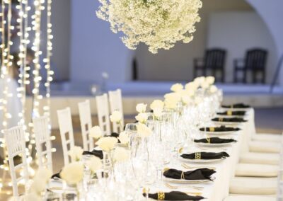 Hochzeitstafel mit hängenden weißen Blumenkugeln und Lichtervorhang im Cortijo