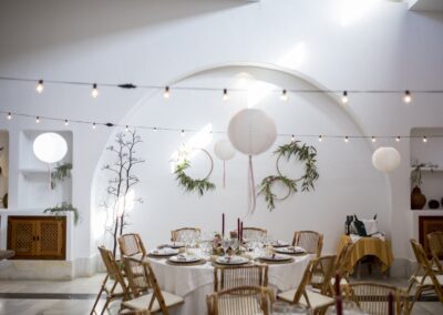 Weißer Festsaal des Cortijo mit Tonnendecke, Lichterketten und runden Hochzeitstischen