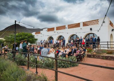 Hochzeitsgäste auf der Terrasse des Cortijo unter der weißen Bogenarkade