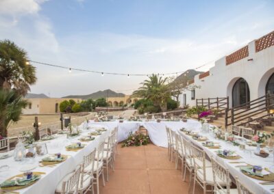 Lange Hochzeitstafeln vor der weißen Bogenarkade des Cortijo