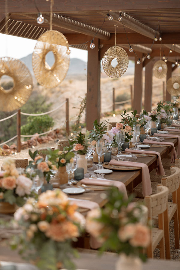 Gedeckte Boho-Langtafel mit Blumen und Rattandeko