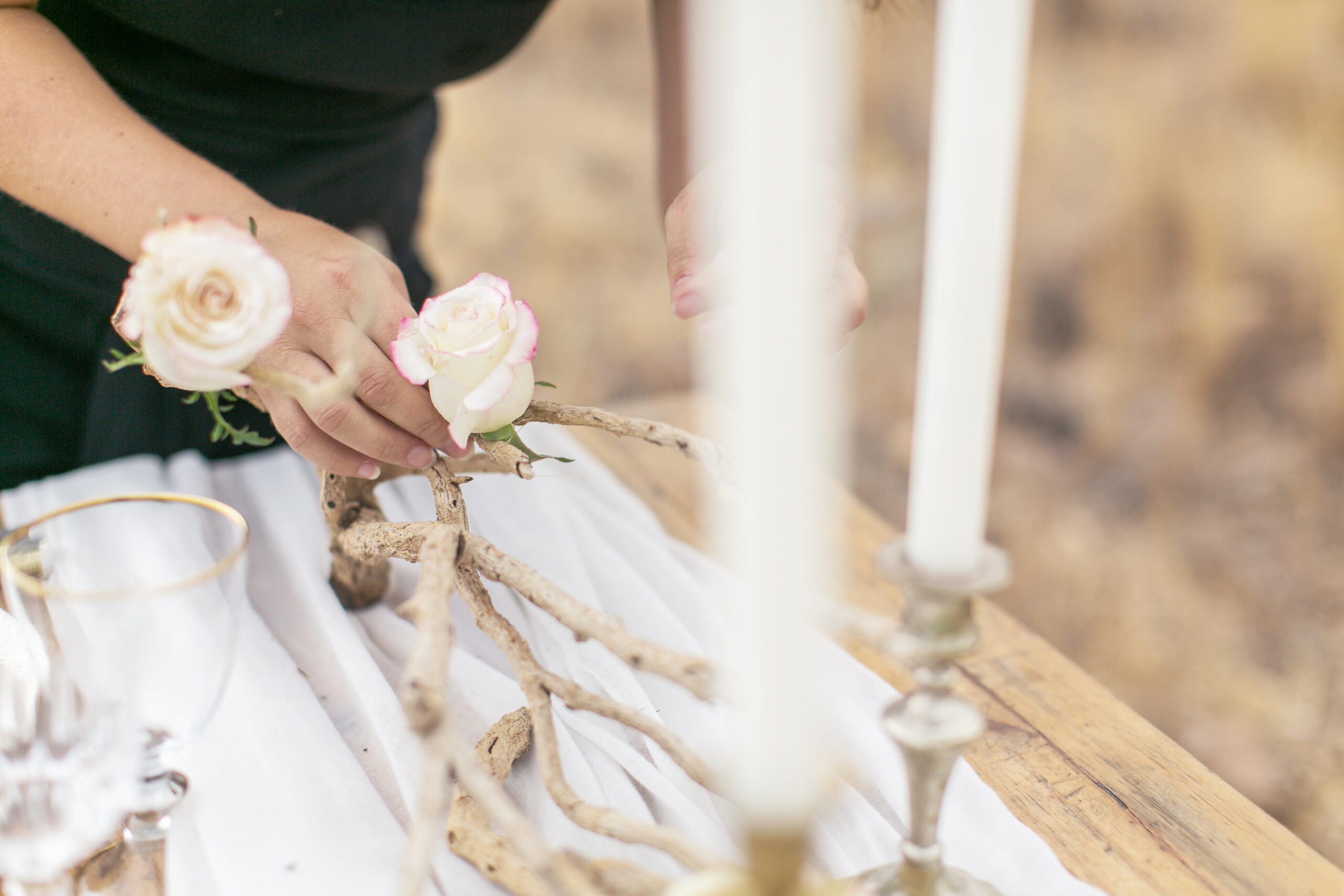 Kerzen und Rosen werden für den Boho-Tisch arrangiert