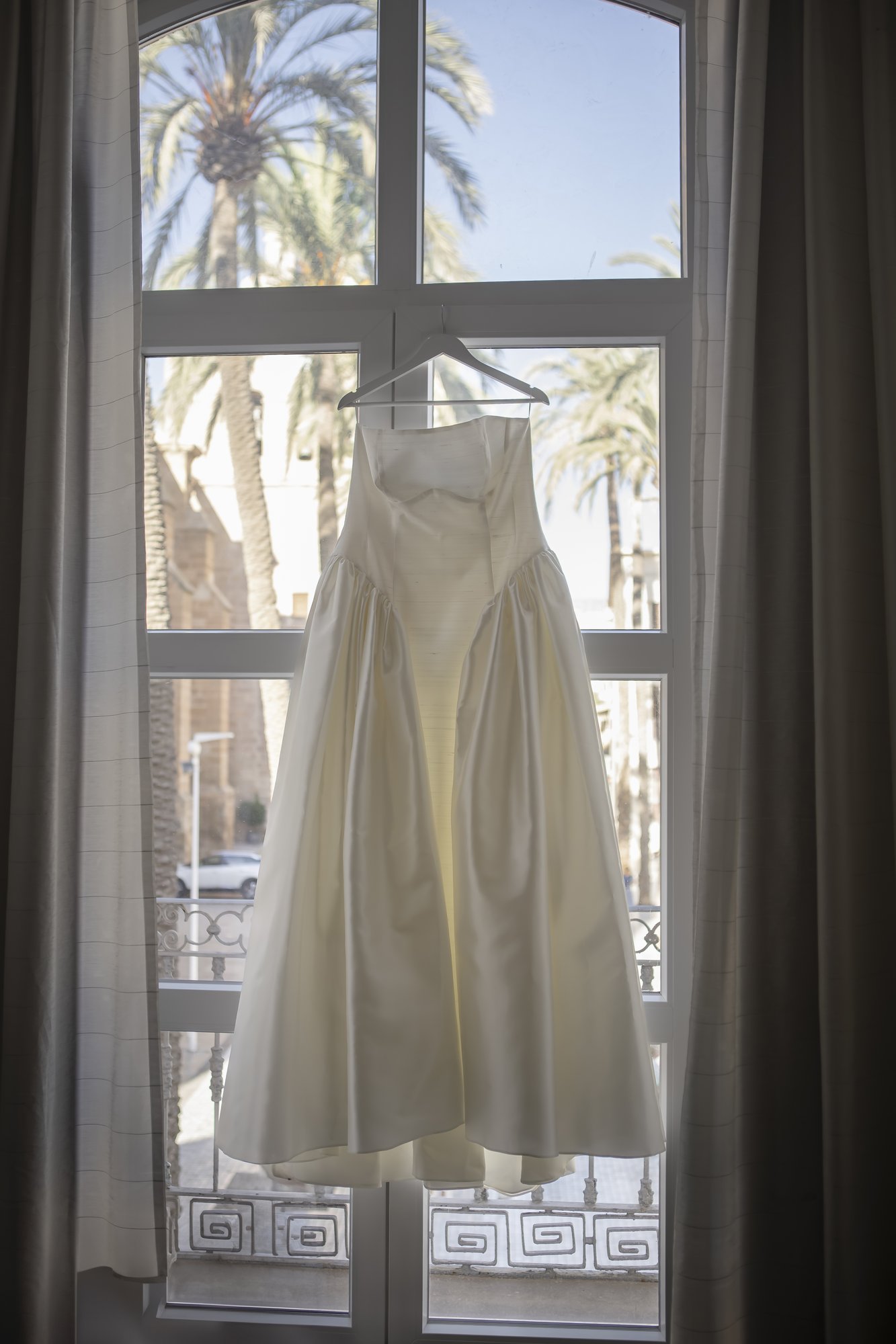 Brautkleid hängt am Fenster mit Palmenblick, Getting Ready in Almería
