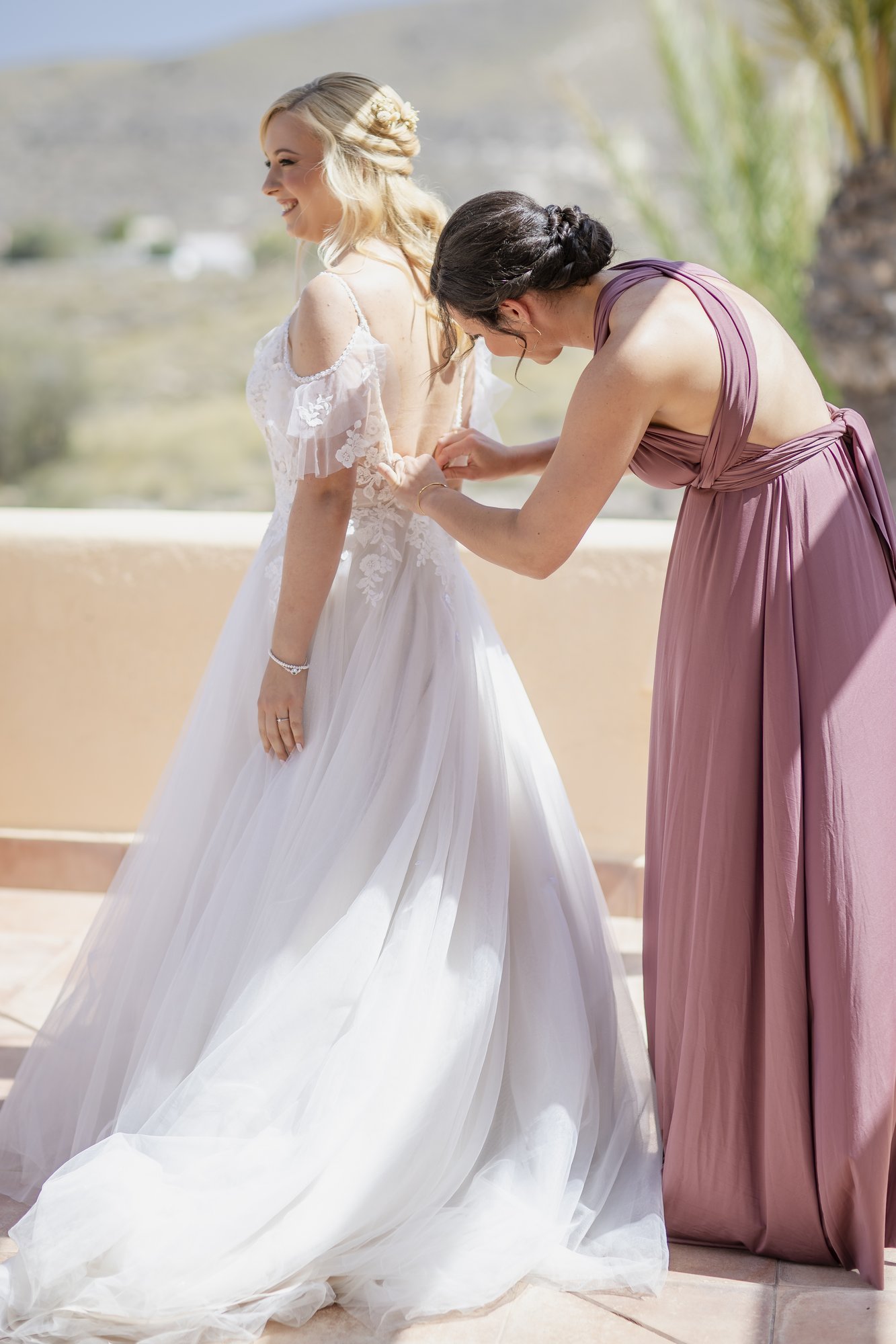 Bridesmaid closing the wedding dress on the terrace, wedding Agua Amarga